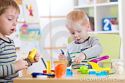 Happy children playing with plasticine at home or day care center Stock Photo