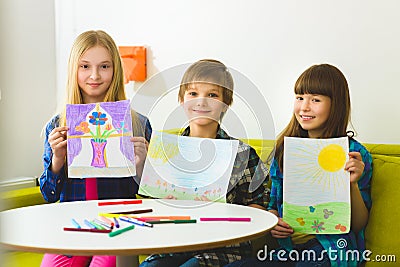 Happy children show their pictures drawn. Indoor at room Stock Photo