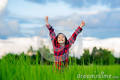 Happy children rise hand up to sky and smile in rice field of organic farmland Stock Photo