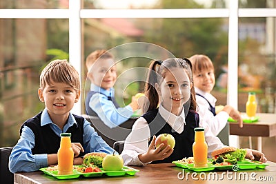 Happy children at table healthy food in school canteen Stock Photo