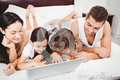 Happy children using laptop with parents on bed at home Stock Photo