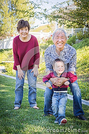 Happy Chinese Grandparents Having Fun with Their Mixed Race Grandson Outside Stock Photo