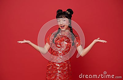 Happy Chinese new year. Little asian child wearing traditional cheongsam qipao dress with gesture of welcome chinese new year 2024 Stock Photo