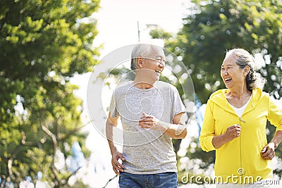 Happy chinese senior couple running outdoors Stock Photo