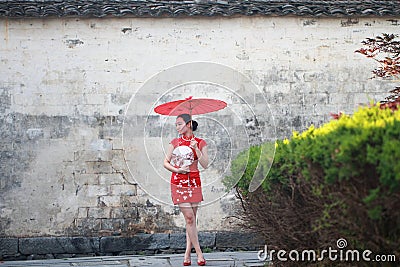 Happy Chinese woman in red cheongsam tour at ancient town Stock Photo