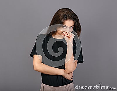 Happy chuckling fun business beautiful woman covering the mouth the hand in black casual t-shirt on grey studio background with Stock Photo