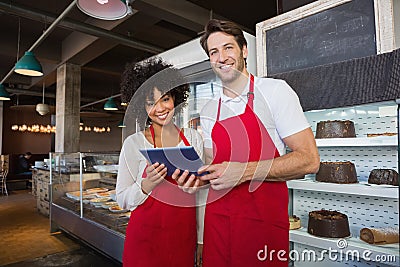 Happy co-workers in red apron holding tablet Stock Photo