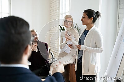 Happy colleagues applauding, thanking young indian female speaker. Stock Photo