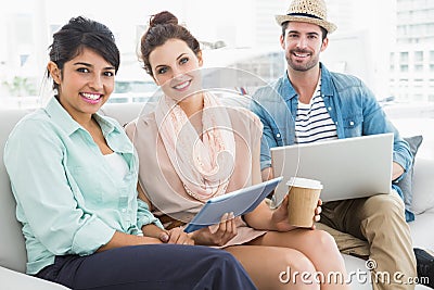 Happy colleagues sitting on couch looking at camera Stock Photo