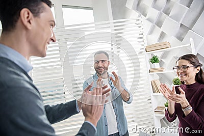 Happy colleagues standing in the office and clapping Stock Photo
