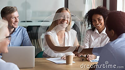 Happy caucasian manager and african client handshaking at group meeting Stock Photo