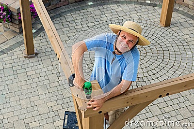 Happy confident man erecting a new outdoor gazebo Stock Photo