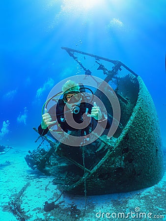 A happy Scuba diver explores a sunken shipwreck in the mediterranean sea Stock Photo