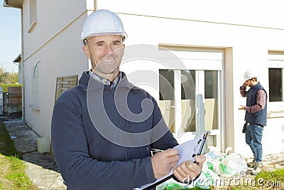 Happy construction inspector on building site writing on clipboard Stock Photo