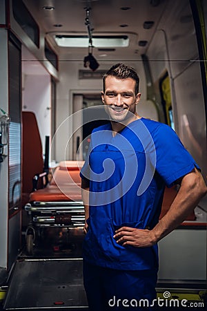 Happy corpsman standing and looking at the camera and smiling, ambulance car in the background Stock Photo