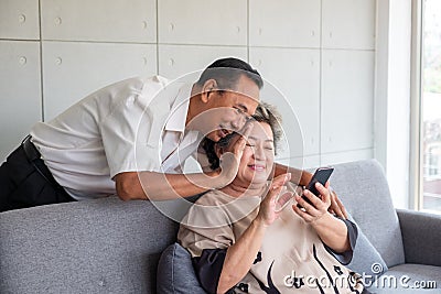 Happy couple asian senior retired using mobile tablet application technology for social network among friends community via Stock Photo