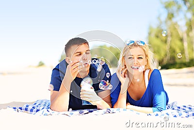 Happy couple blowing bubbles at the beach Stock Photo