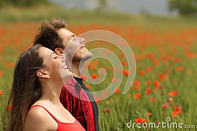 Happy couple breathing fresh air in a red field Stock Photo