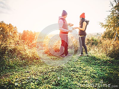 Happy couple in casual clothes on nature drinking tea outdoors, having picnic in fall season smiling laughing. Two people at sunse Stock Photo