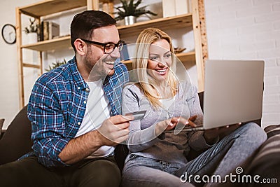 Couple communicating while using credit card and laptop for online shopping at home Stock Photo