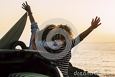 Happy couple of curly girl have fun together and look at the sunset in front of the ocean in tropical beautiful vacation outdoor Stock Photo