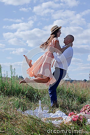 Happy couple dancing in the field. brunette in cream dress and bald man in white shirt and blue pants. love story. husband and Stock Photo