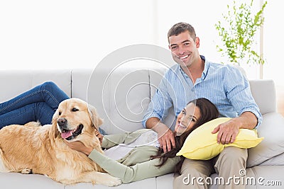 Happy couple with dog relaxing on sofa Stock Photo