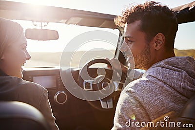 Happy couple driving in car with sunroof open, passenger POV Stock Photo