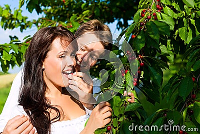 Happy couple eating cherries in summer Stock Photo