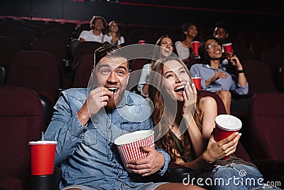 Happy couple eating popcorn and laughing Stock Photo