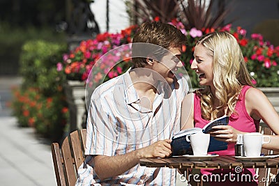 Happy Couple With Guidebook Sitting At Outdoor Cafe Stock Photo