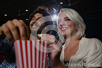 Couple having popcorn while watching movie in theatre Stock Photo