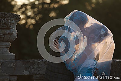 happy couple hugging and kissing each other under veil on background sunset Stock Photo