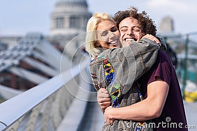 Happy couple hugging by Millennium bridge, River Thames, London. Editorial Stock Photo