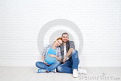 Happy couple husband and pregnant wife near blank brick wall Stock Photo