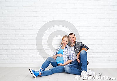 Happy couple husband and pregnant wife near blank brick wall Stock Photo