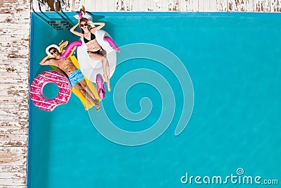 Couple with inflatable rings and mattress in swimming pool, top view. Summer vacation Stock Photo