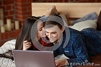 Happy couple with laptop shopping online at home, browsing internet in bed, smiling and having fun Stock Photo