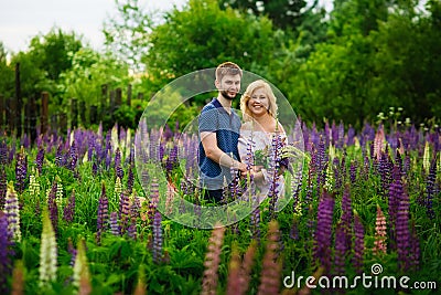 A happy couple in love embraces in a Lupin field. Blooming purple flowers of lupine Stock Photo
