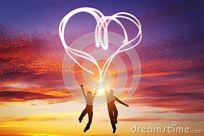 Happy couple in love jump making heart symbol of light Stock Photo