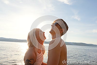 Happy couple in love laughing at the beach against sun Stock Photo