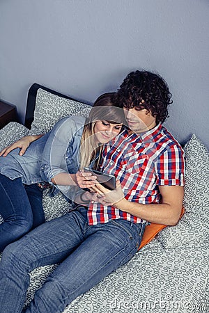 Happy couple in love looking electronic tablet on bed Stock Photo