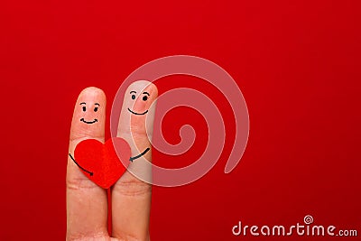 Happy couple in love with painted smiley holding red heart - Image Stock Photo