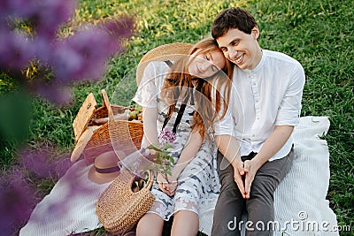 Happy couple in love on a picnic, sits resting on the green grass. Stock Photo