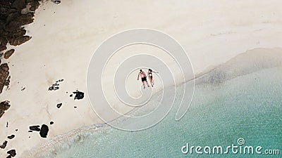 Happy couple lying on the tropical beach in Thailand, relaxing, celebrating honeymoon. Turquoise mint color clear water. Drone Stock Photo