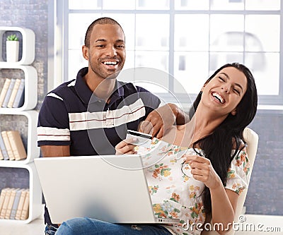 Happy couple online shopping at home laughing Stock Photo