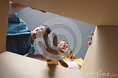 Happy couple opening a cardboard box and looking inside Stock Photo