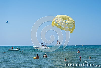 Happy couple Parasailing on Tropical Beach in summer. Couple under parachute hanging mid air. Having fun. Tropical Paradise. Posit Stock Photo