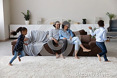Happy couple of parents watching two energetic hyperactive little kids Stock Photo