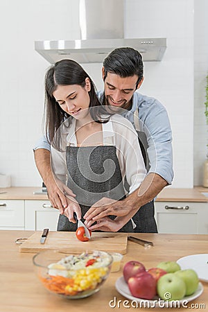 Happy couple preparing food at home, young couple cutting vegetables together at kitchen counter Stock Photo